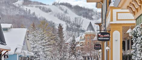 A snow-covered street with a building labeled "Magnes Italian Kitchen" and a mountain in the background.