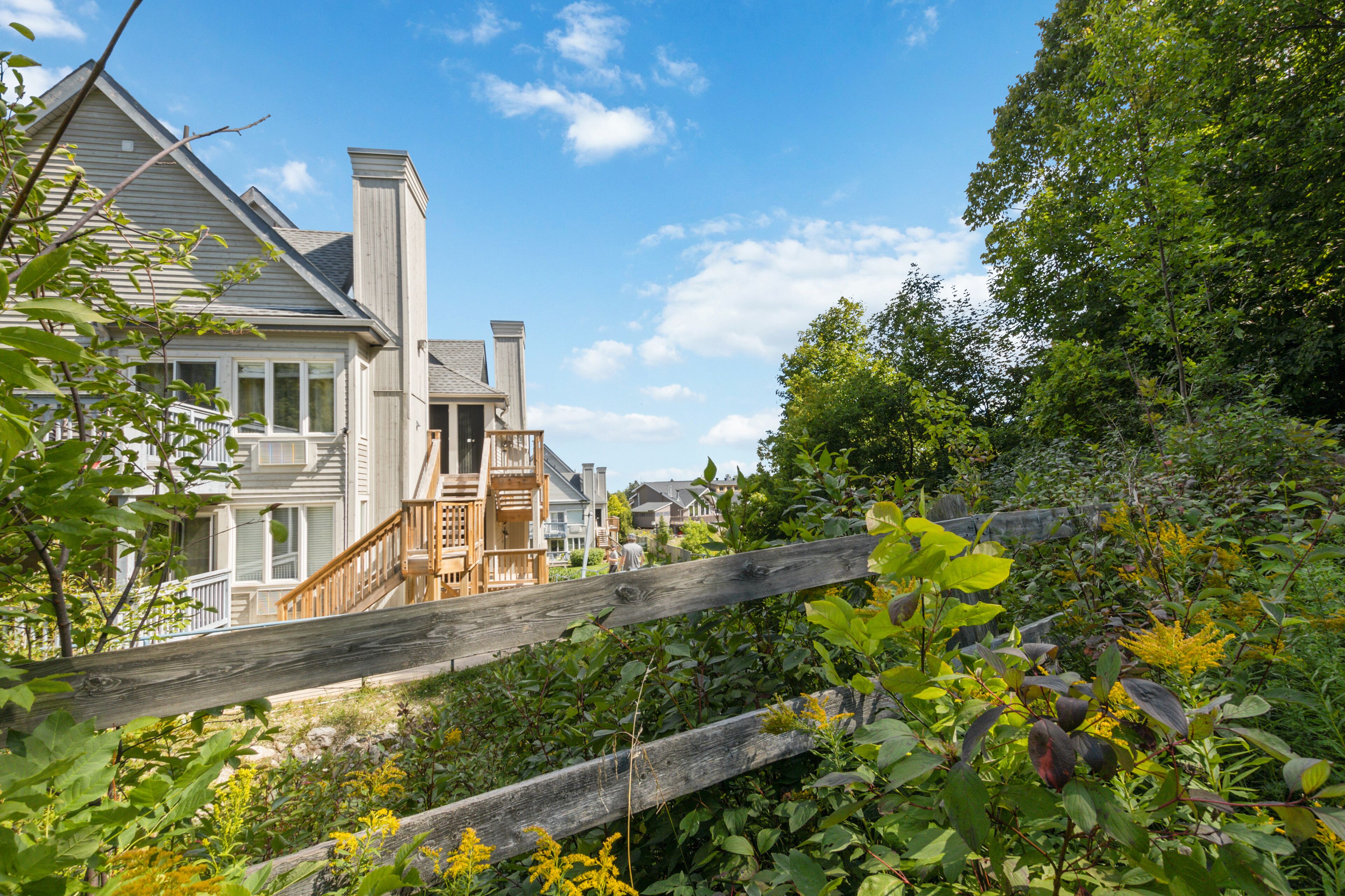 Un quartier résidentiel avec des maisons, une clôture en bois et une végétation luxuriante.