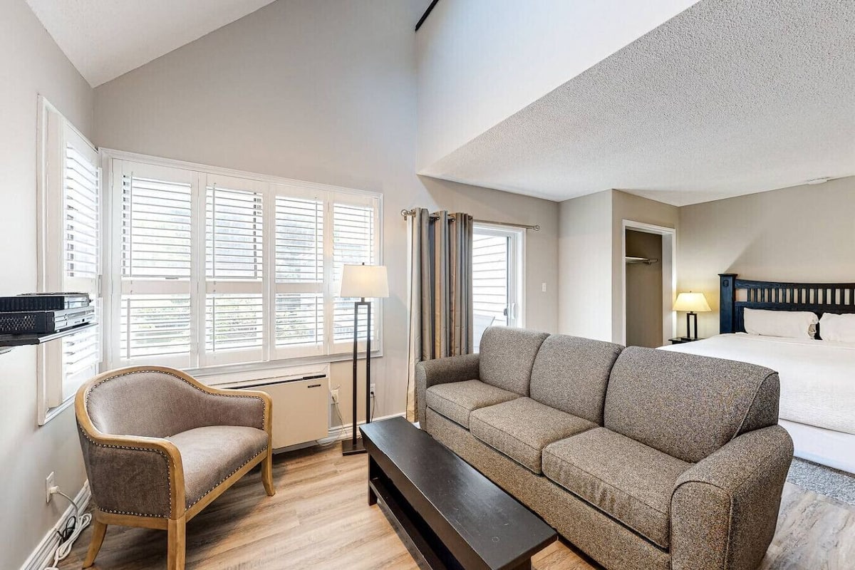 Una habitación de hotel con cama, sofá, sillón, escritorio y lámpara.