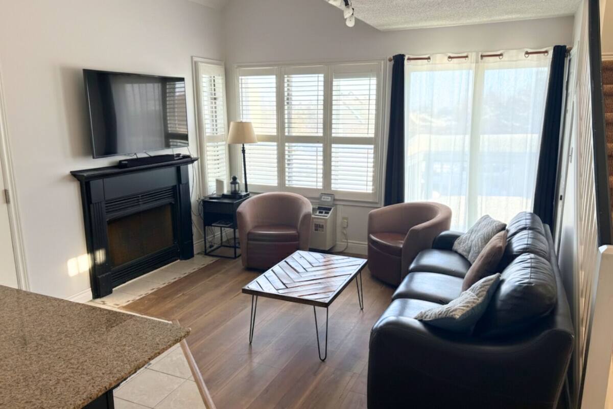 Una sala de estar con chimenea, televisor, sofá y una mesa.