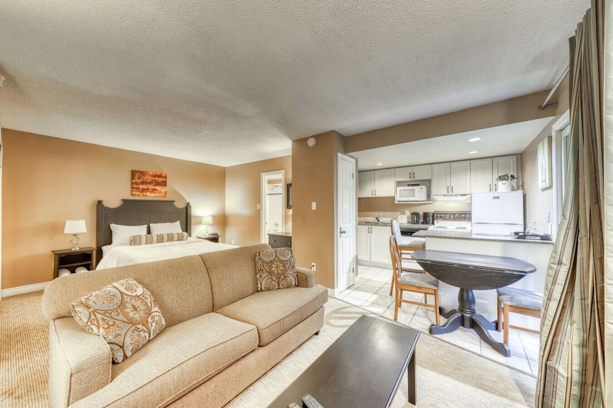 Una habitación de hotel con cama, sofá, mesa de comedor y kitchenette.