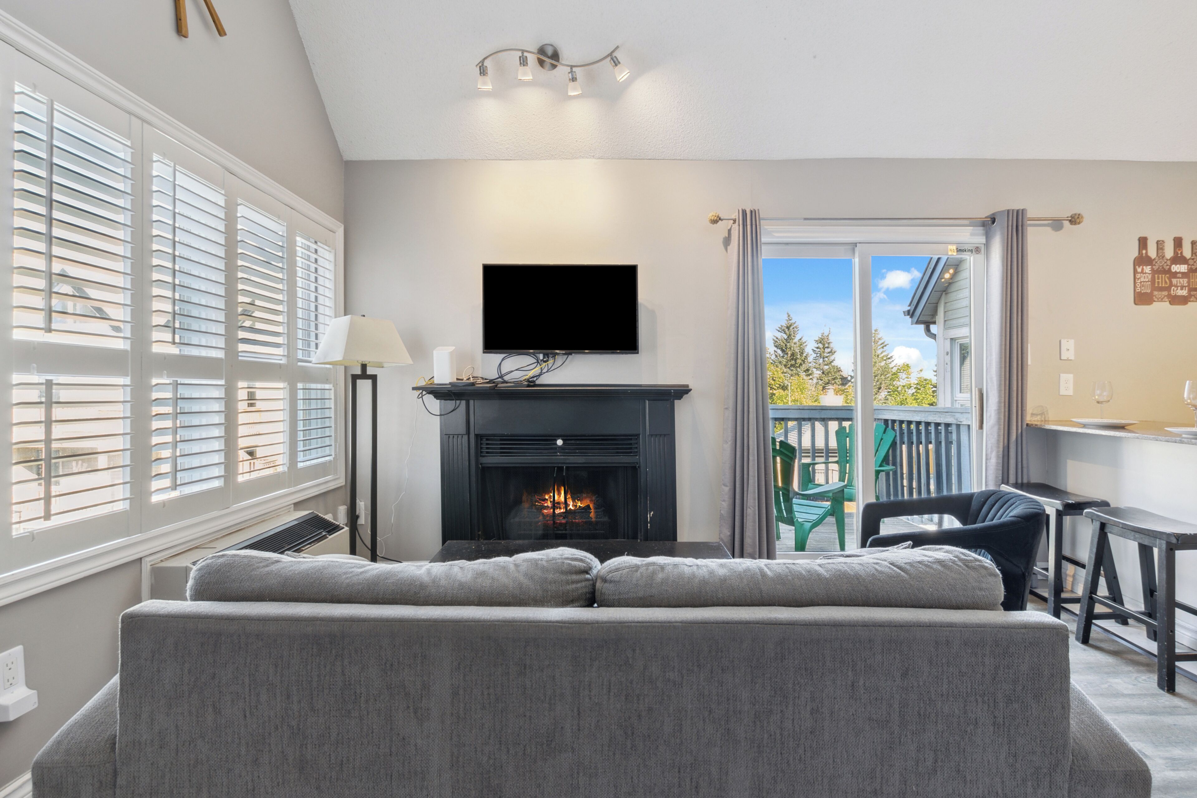 Un salon doté d’une cheminée, d’un téléviseur à écran plat et d’un balcon aménagé avec du mobilier d’extérieur.