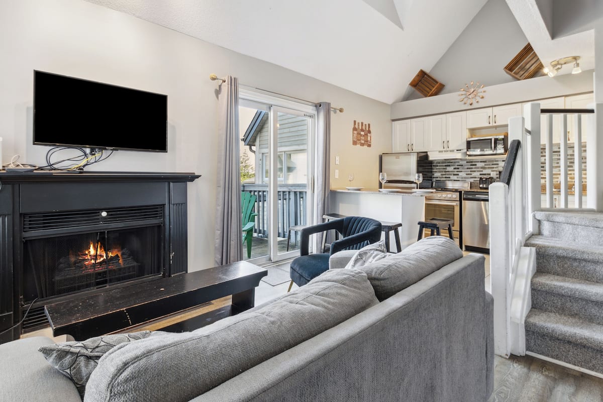 Una sala de estar moderna con chimenea, un televisor de pantalla plana y un sofá gris.