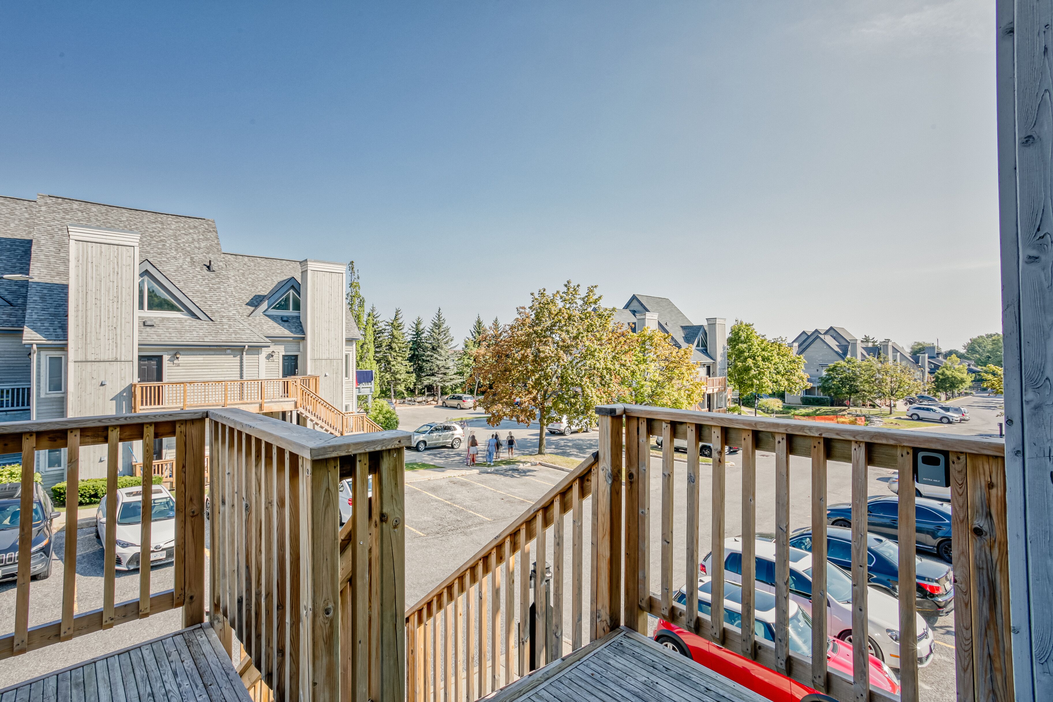 A residential area with a wooden deck, houses, and parked cars.