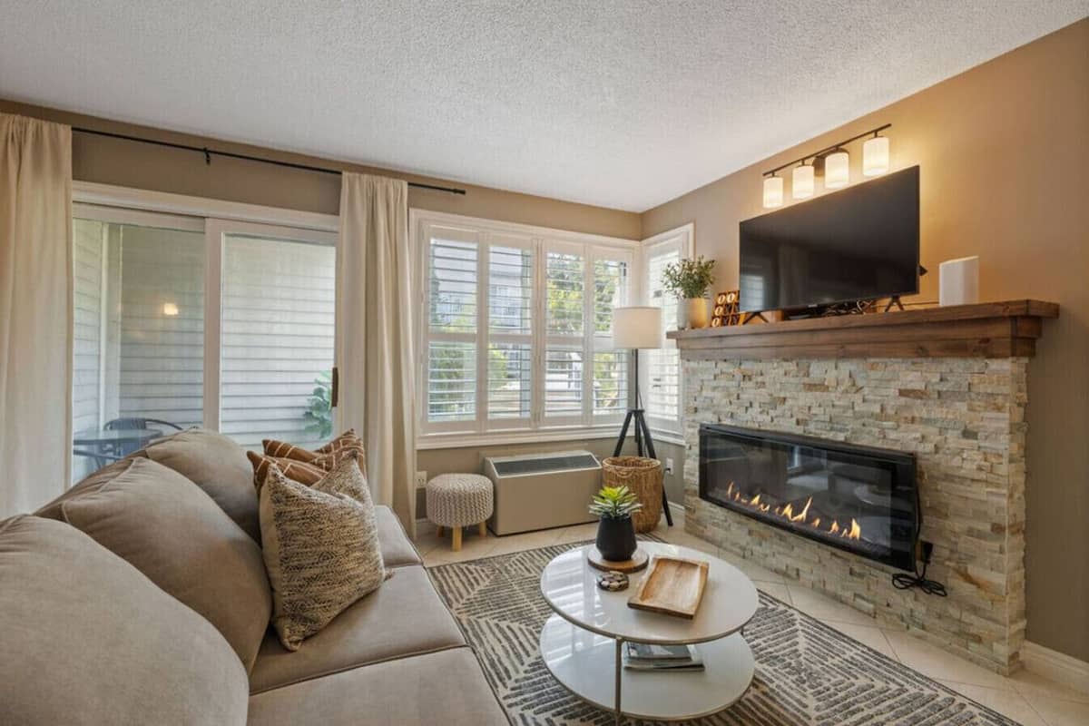 Una sala de estar con chimenea, sofá, mesa de centro y televisor.