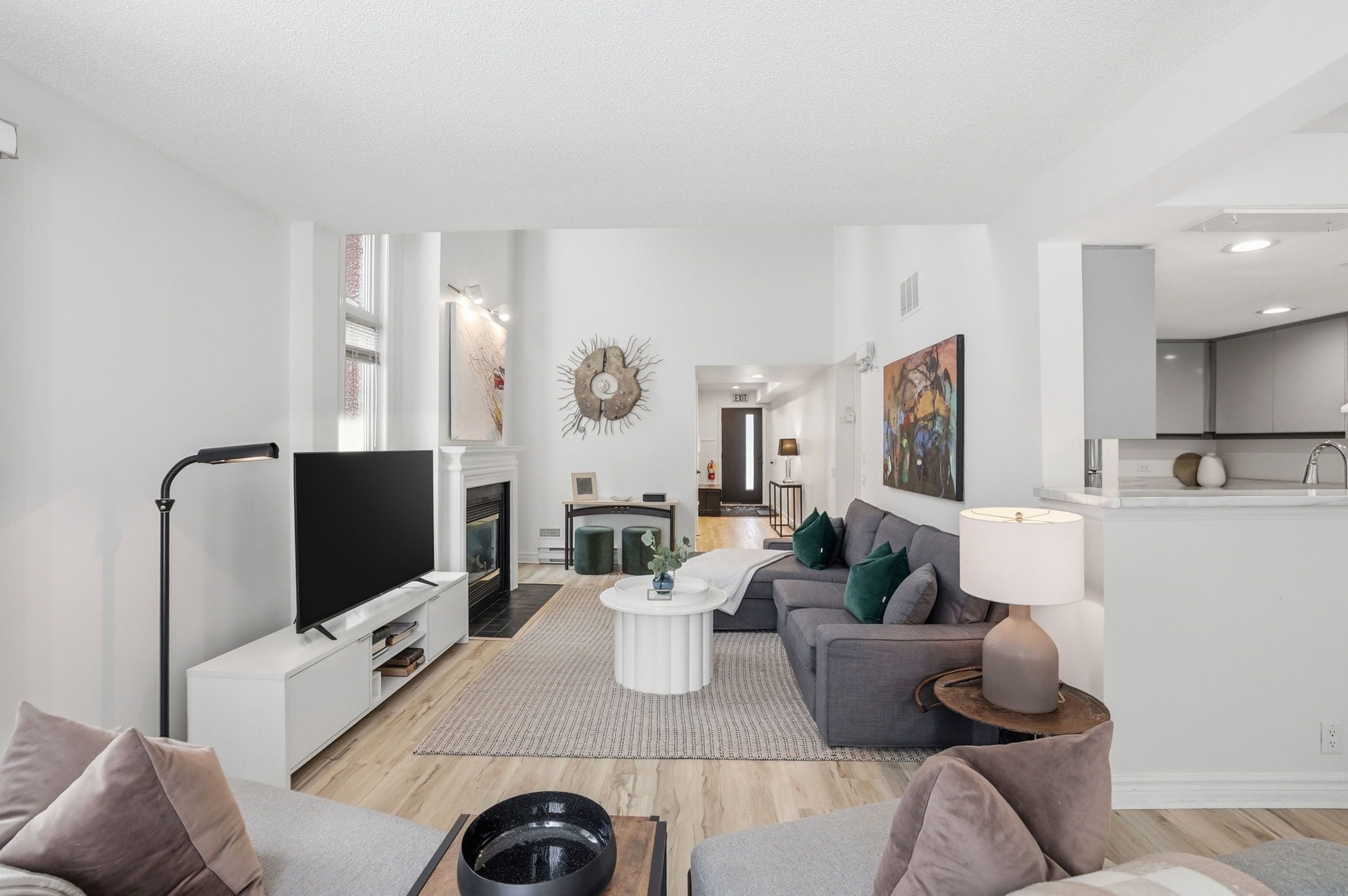 A modern living room with a flat-screen TV, sofa, coffee table, and a fireplace.