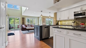 A modern kitchen with white cabinets, stainless steel appliances, and a large island. - Sierra Lane Condos (The Blue Mountains)