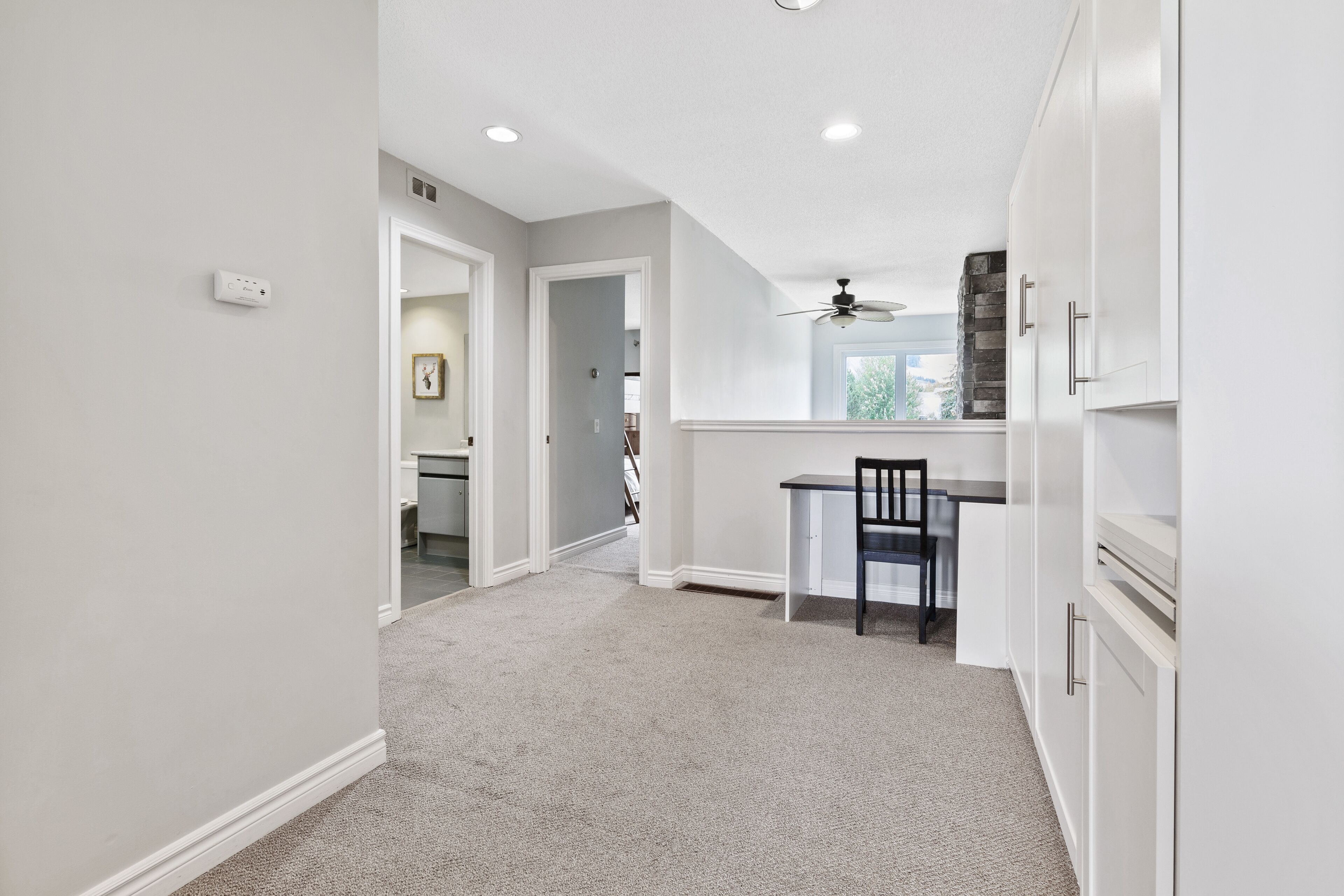 A modern kitchen with white cabinetry, a dining area with a table and chairs, and a ceiling fan.