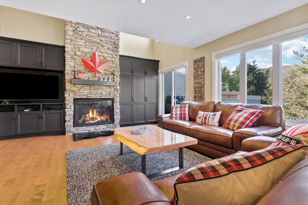 A living room with a stone fireplace, leather sofa, and a flat-screen TV.