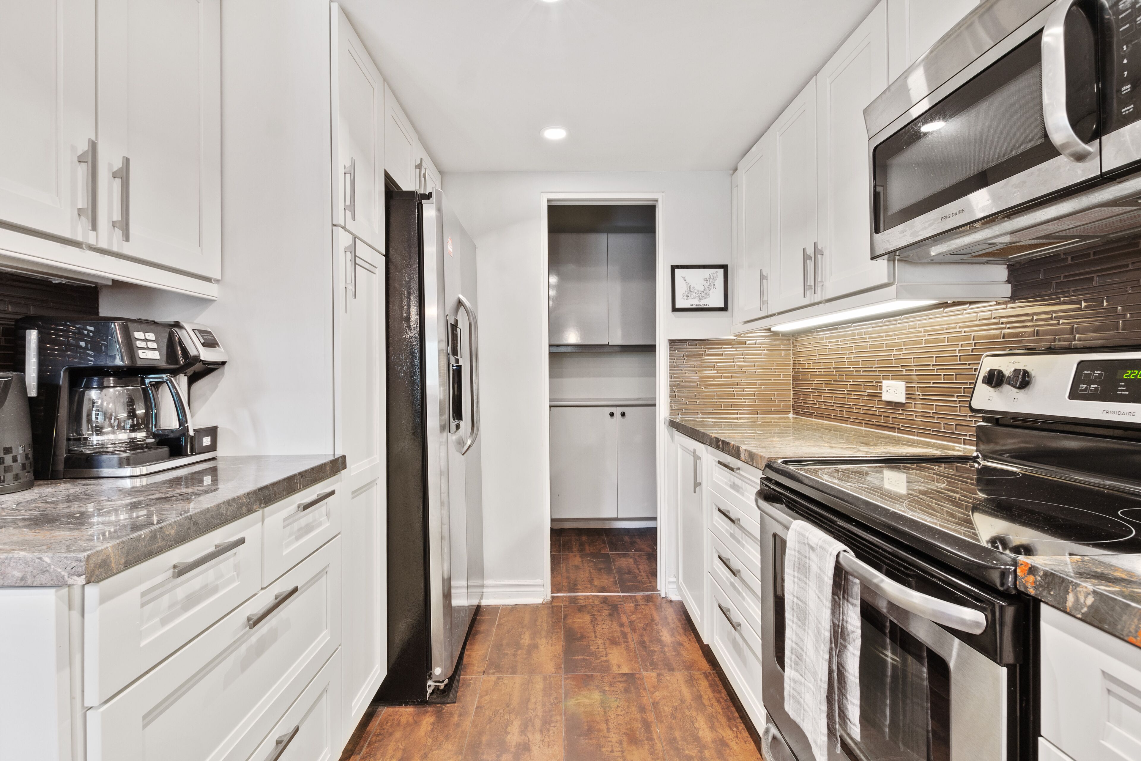 A modern kitchen with white cabinets, stainless steel appliances, and a tiled backsplash.