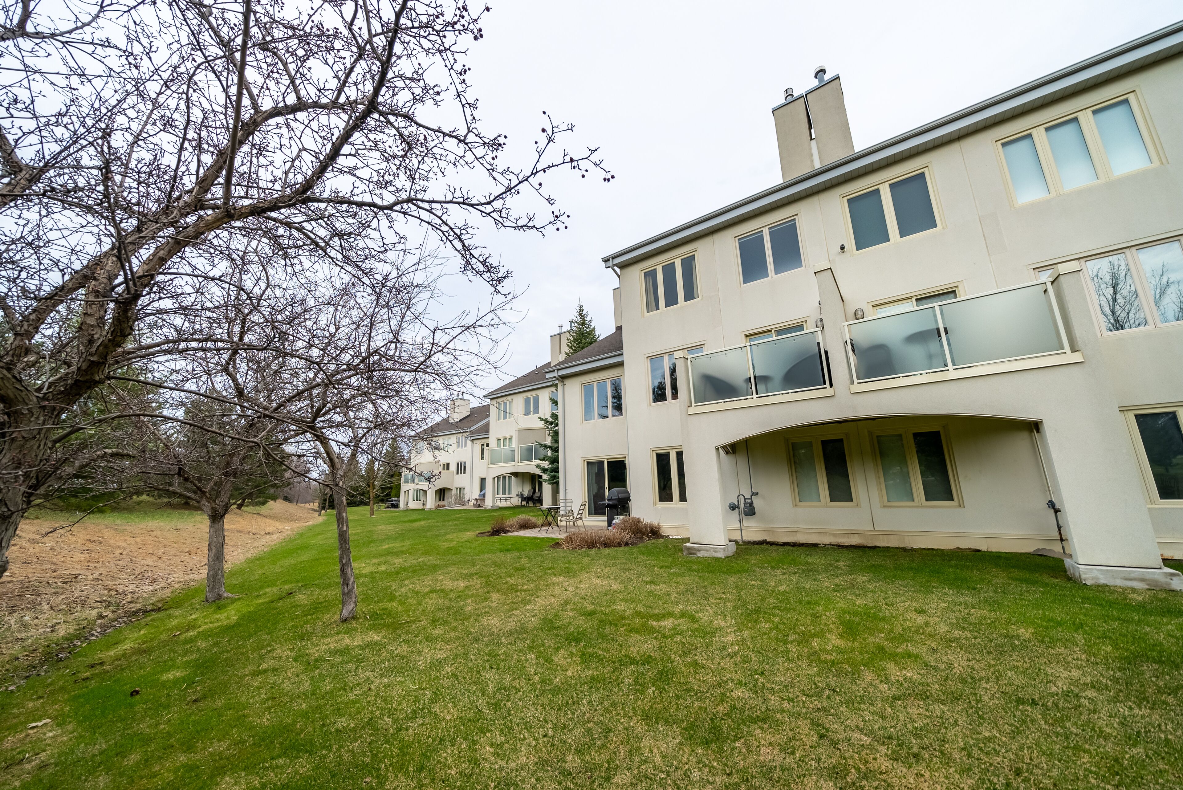 A multi-story residential building with a flat roof, large windows, and a well-maintained lawn.