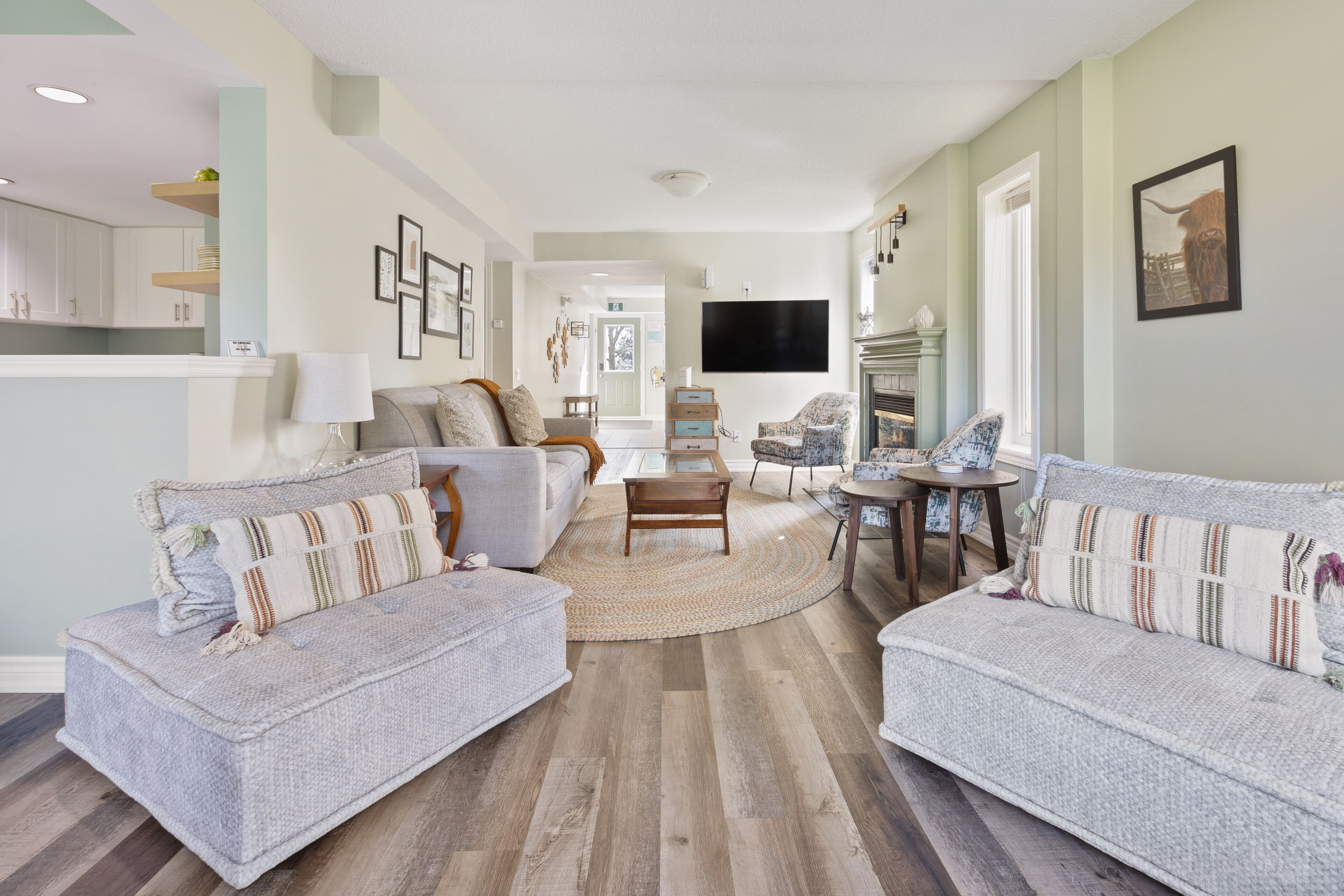A living room with two grey sofas, a coffee table, and a TV mounted on the wall.