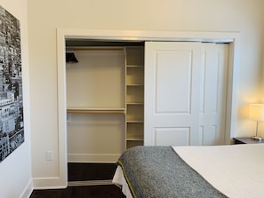 Ein Schlafzimmer mit einem Bett, einem Schrank mit mehreren Ablagen und einer Wandleuchte.