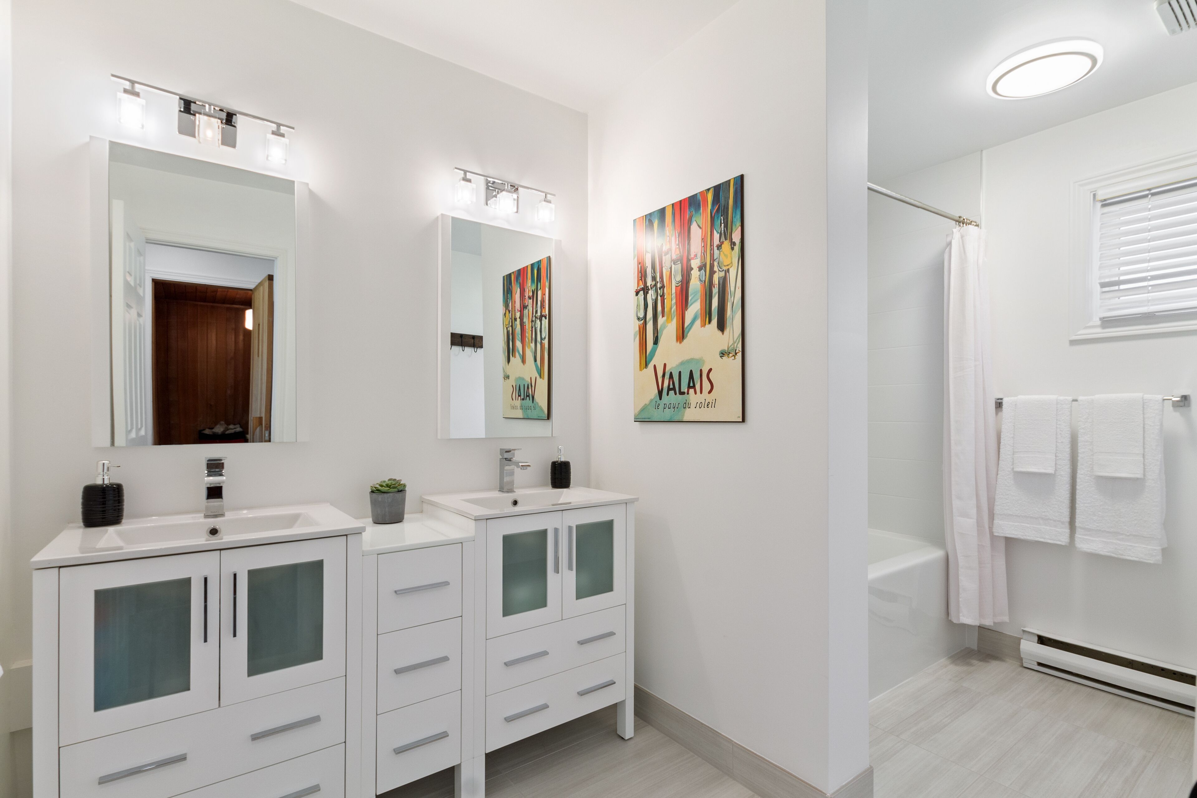 Une salle de bain moderne avec deux lavabos, un grand miroir et une douche.