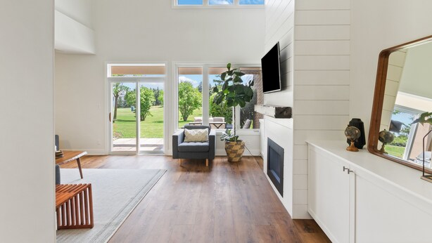 A spacious living room with a fireplace, a large window, and a television. - Wintergreen Condos (The Blue Mountains)
