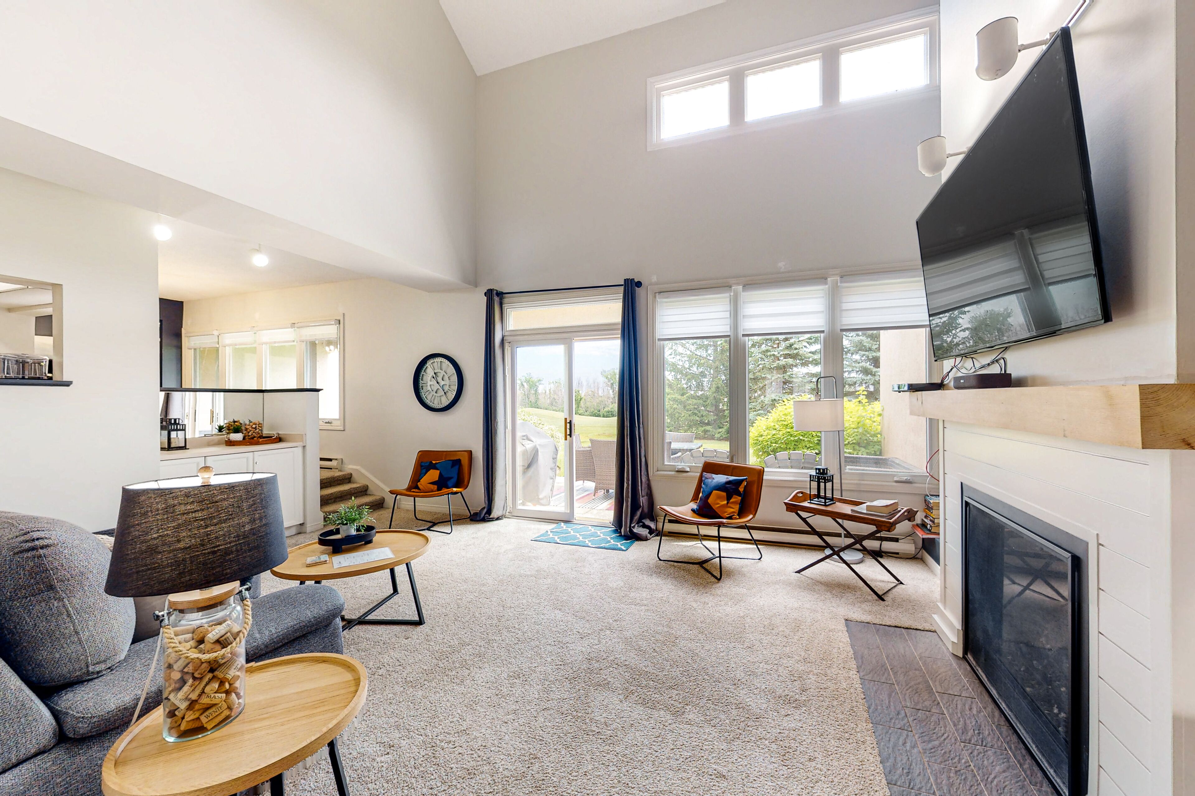 A spacious living room with a fireplace, a large TV mounted on the wall, and a comfortable seating area with a sofa and chairs.
