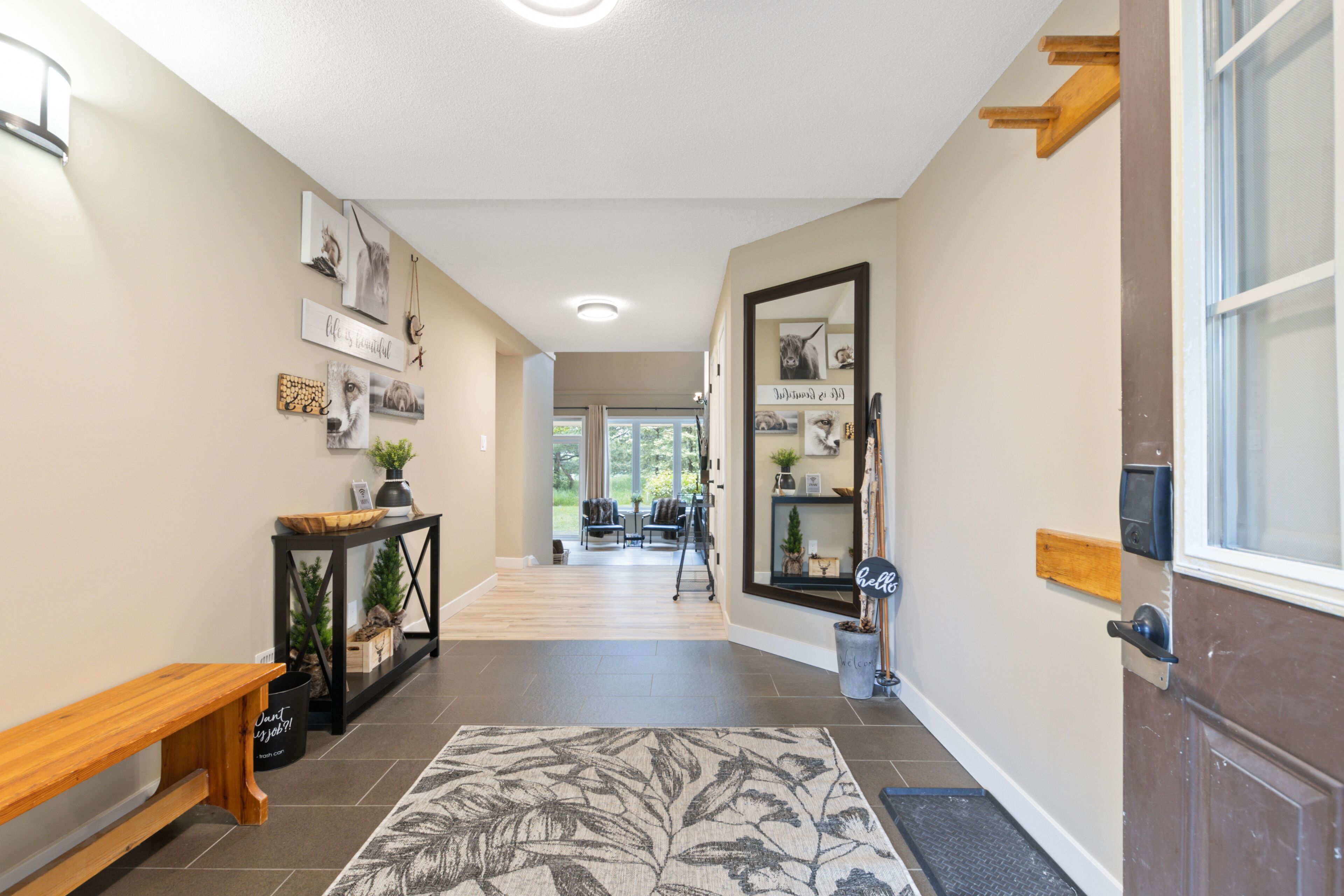 A hallway with a wooden bench, a console table with plants, and a welcome sign.