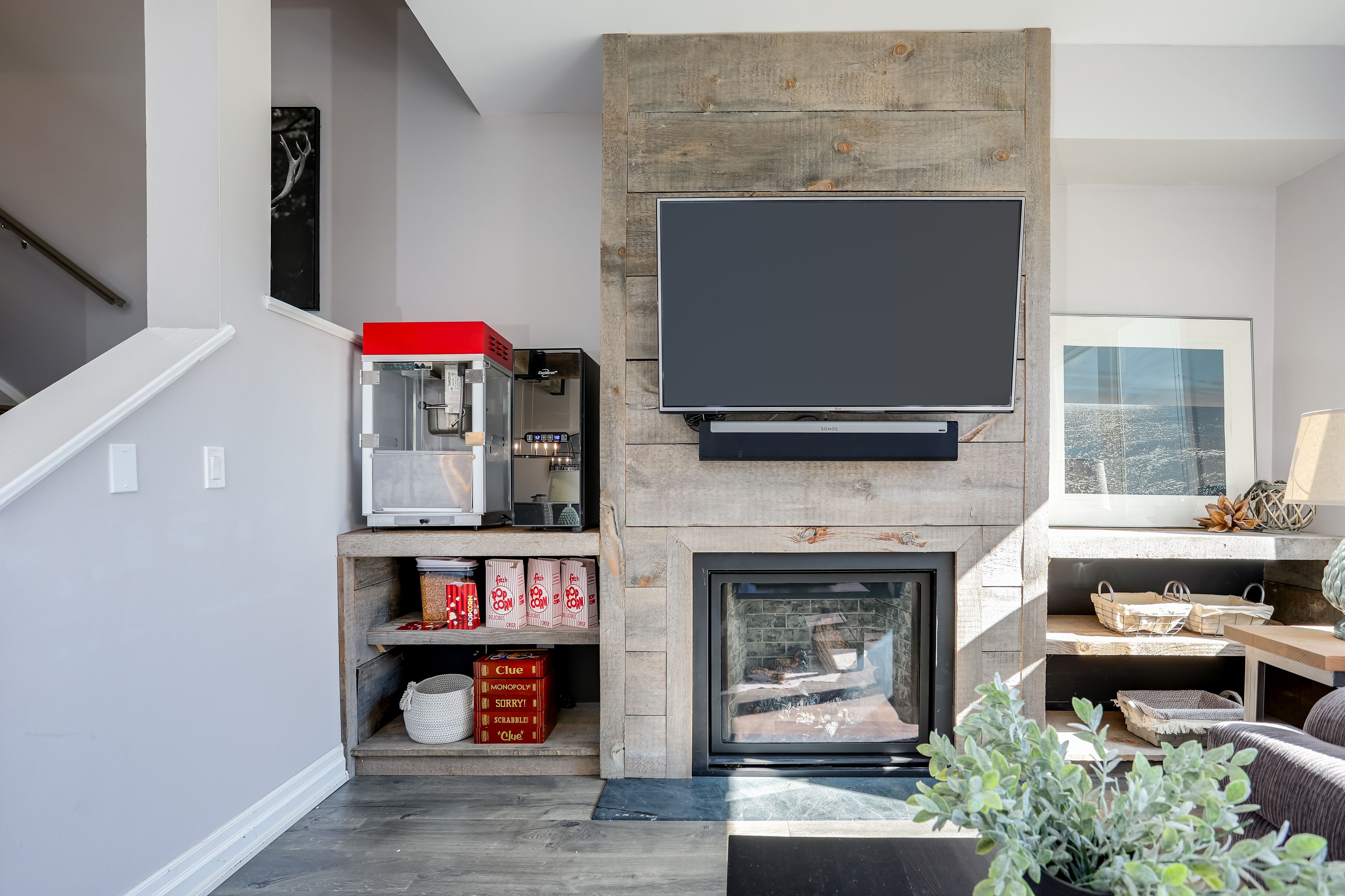 A modern living room with a fireplace, a flat-screen TV mounted above it, and a coffee machine on a shelf.