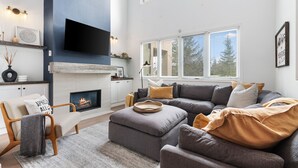 A modern living room with a fireplace, a large flat-screen TV, and a cozy seating area. - Wintergreen Condos (The Blue Mountains)