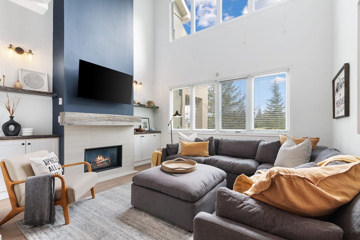 A modern living room with a fireplace, a large flat-screen TV, and a cozy seating area.