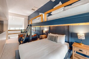 Quarto com beliche, escrivaninha, cadeira e abajur.