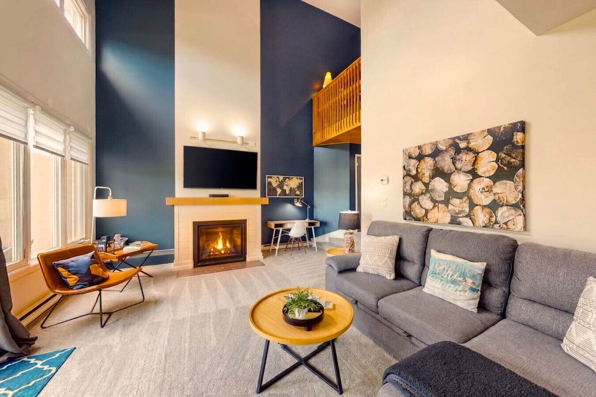 A modern living room with a fireplace, a sofa, a coffee table, and a TV mounted on the wall.