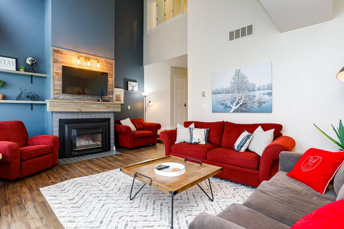 A living room with a fireplace, red sofas, a coffee table, and a large window.
