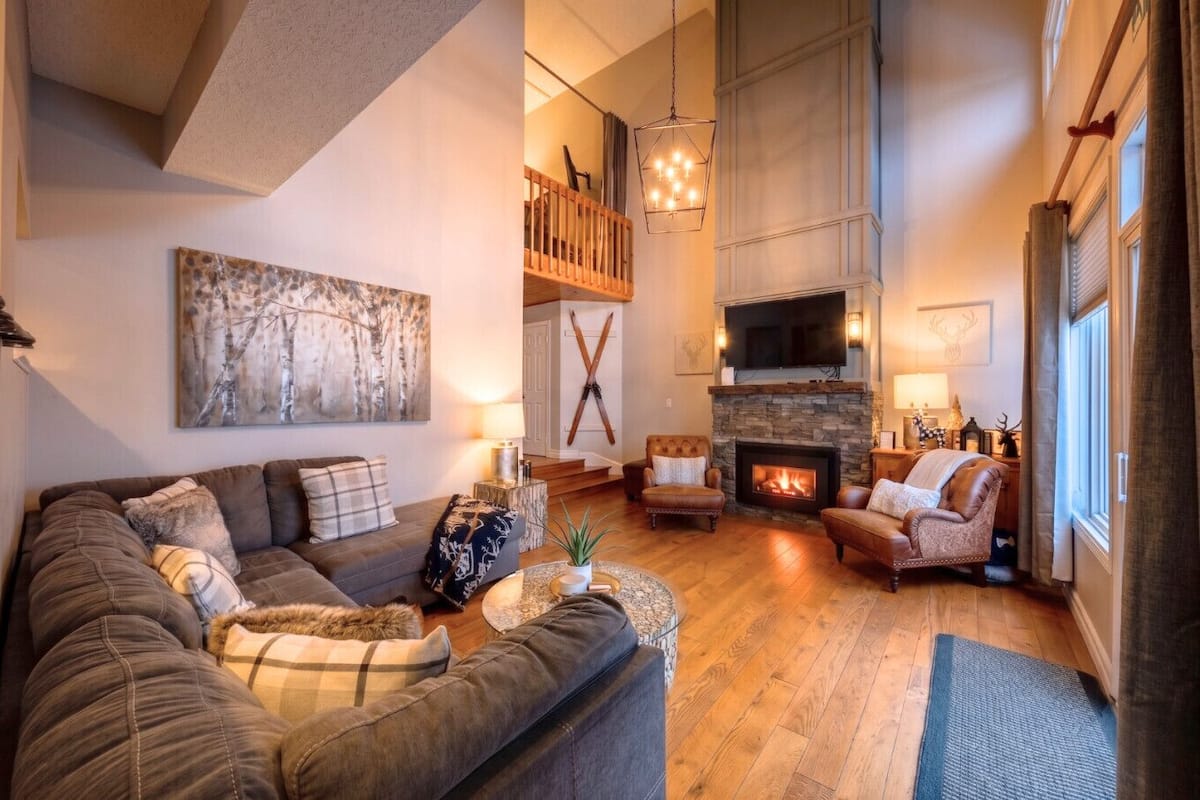 A spacious living room with a fireplace, a large painting, and a cozy seating area.