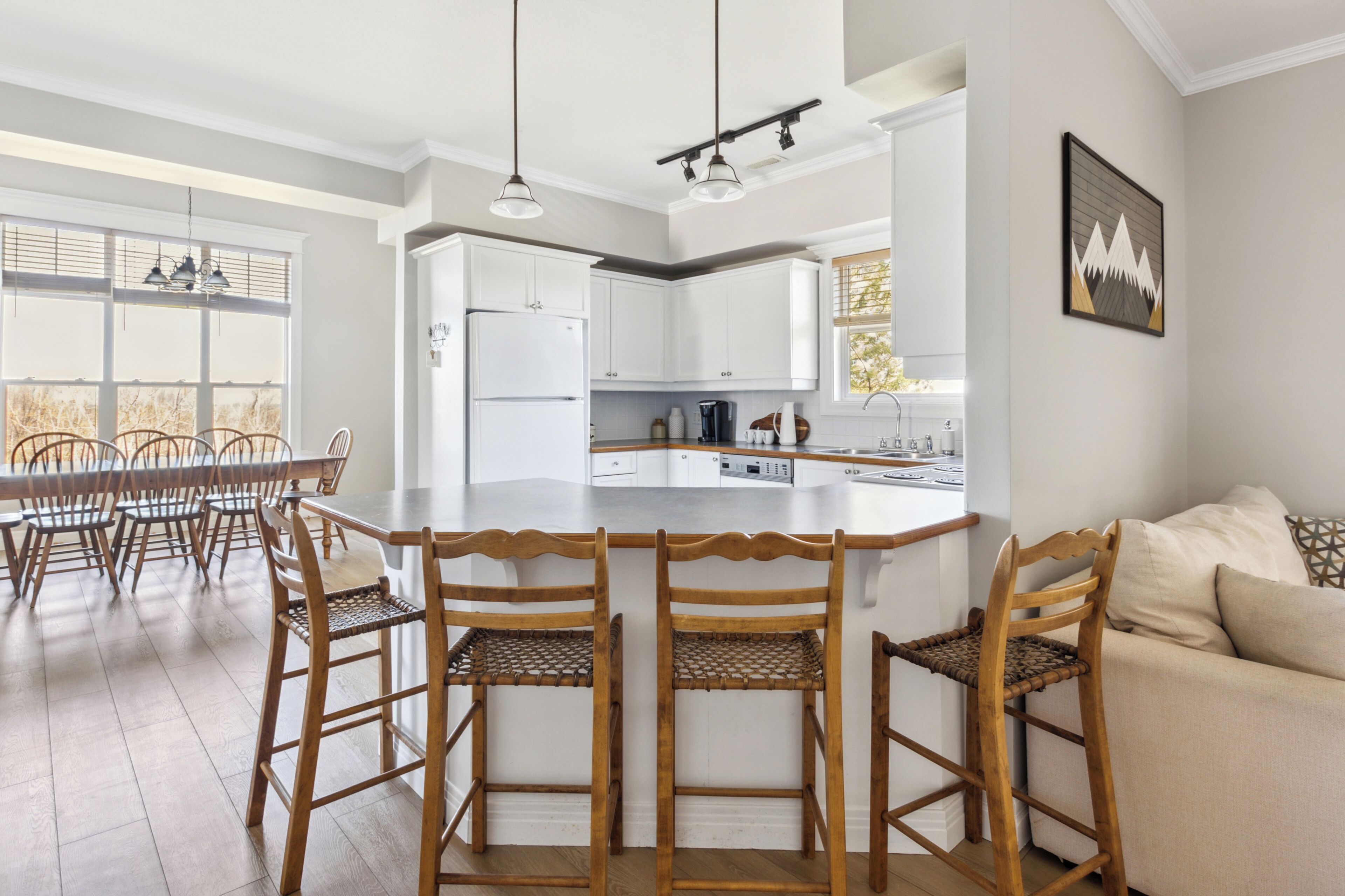 Una cocina moderna con armarios blancos, una isla central y sillas de madera.