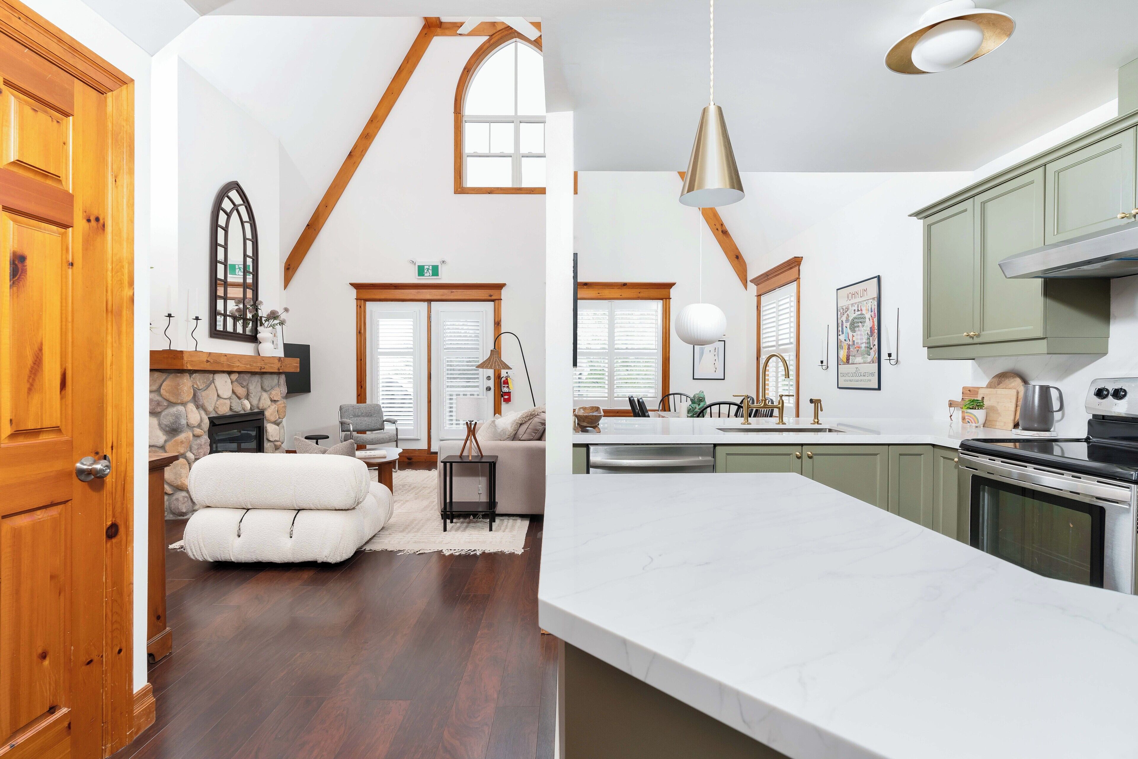 A spacious living area with a stone fireplace, wooden beams, and a large window.
