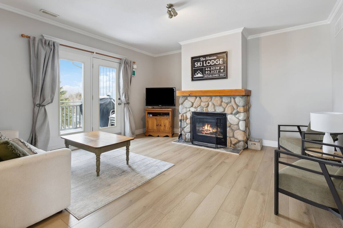 Ein Wohnzimmer mit Kamin aus Stein, einem Flachbildfernseher, einem Couchtisch aus Holz und einer Couch.