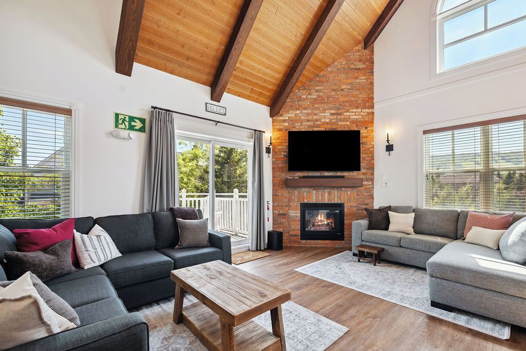 A spacious living room with a fireplace, comfortable seating, and a large window.