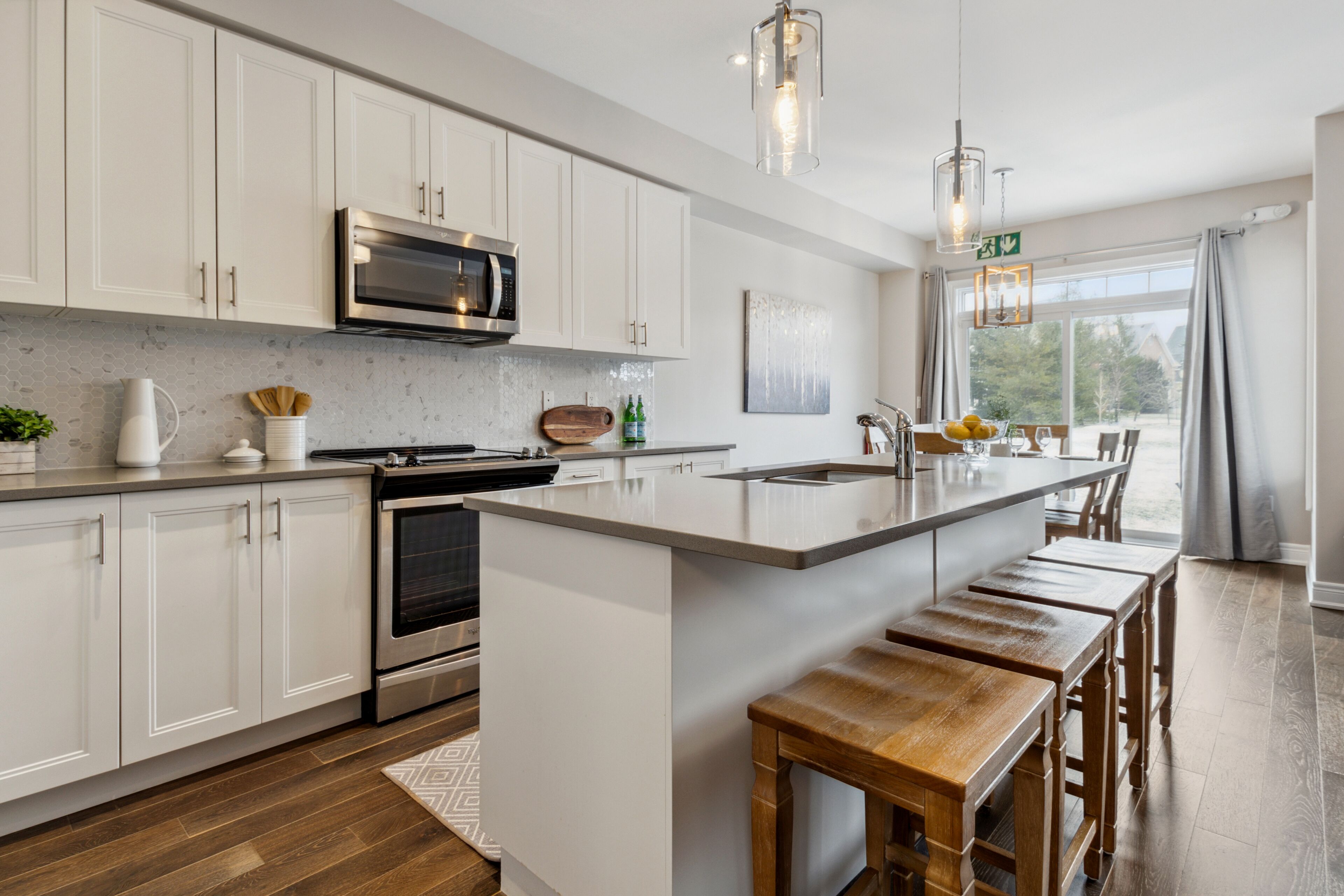 A modern kitchen with white cabinetry, stainless steel appliances, and a large island with bar stools.