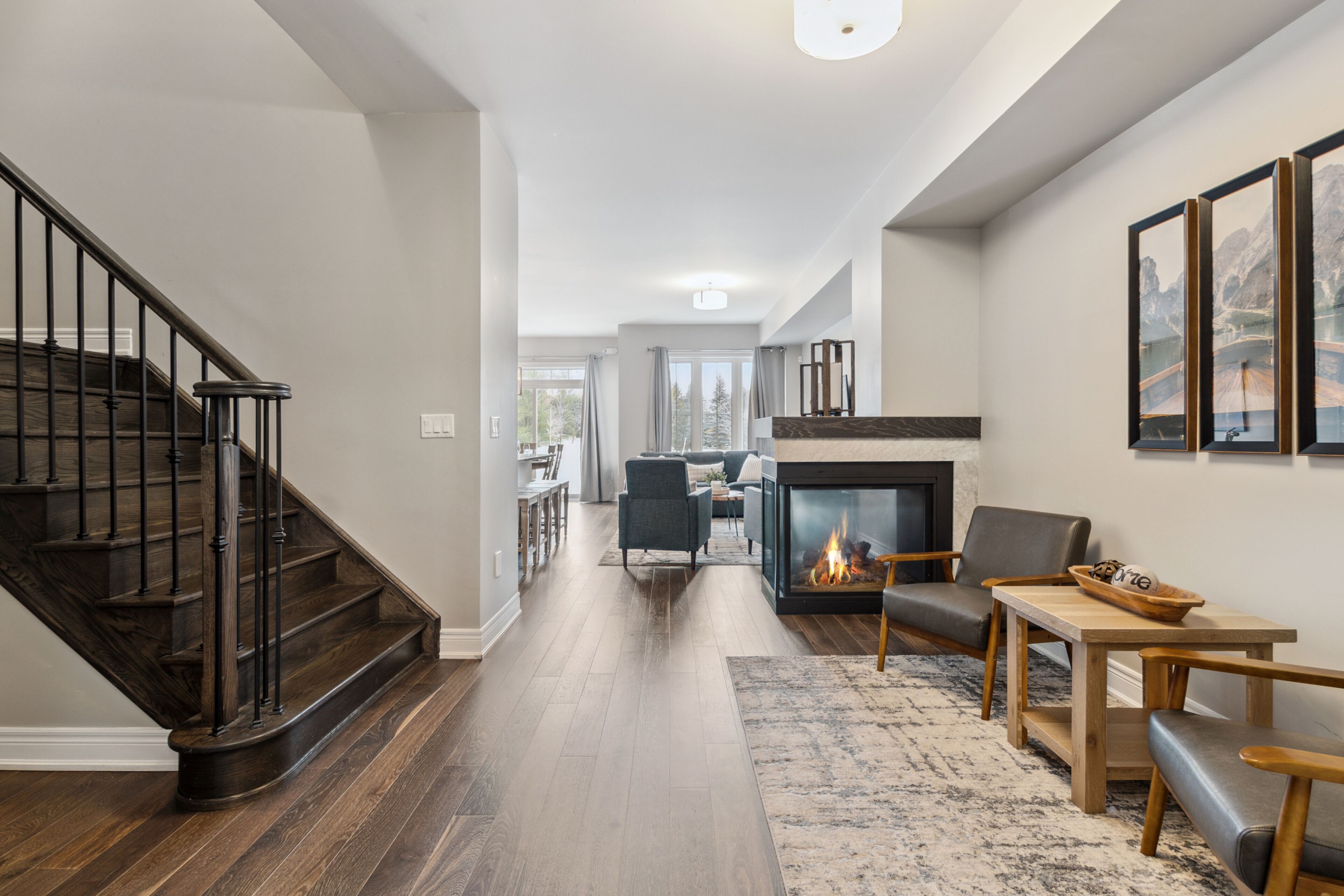 A modern living room with a fireplace, wooden flooring, and a staircase.