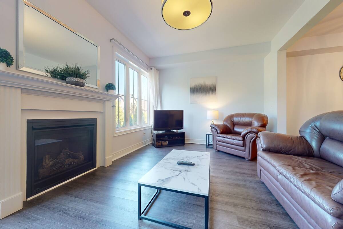 Ein Wohnzimmer mit Kamin, Ledersofa und Fernseher.