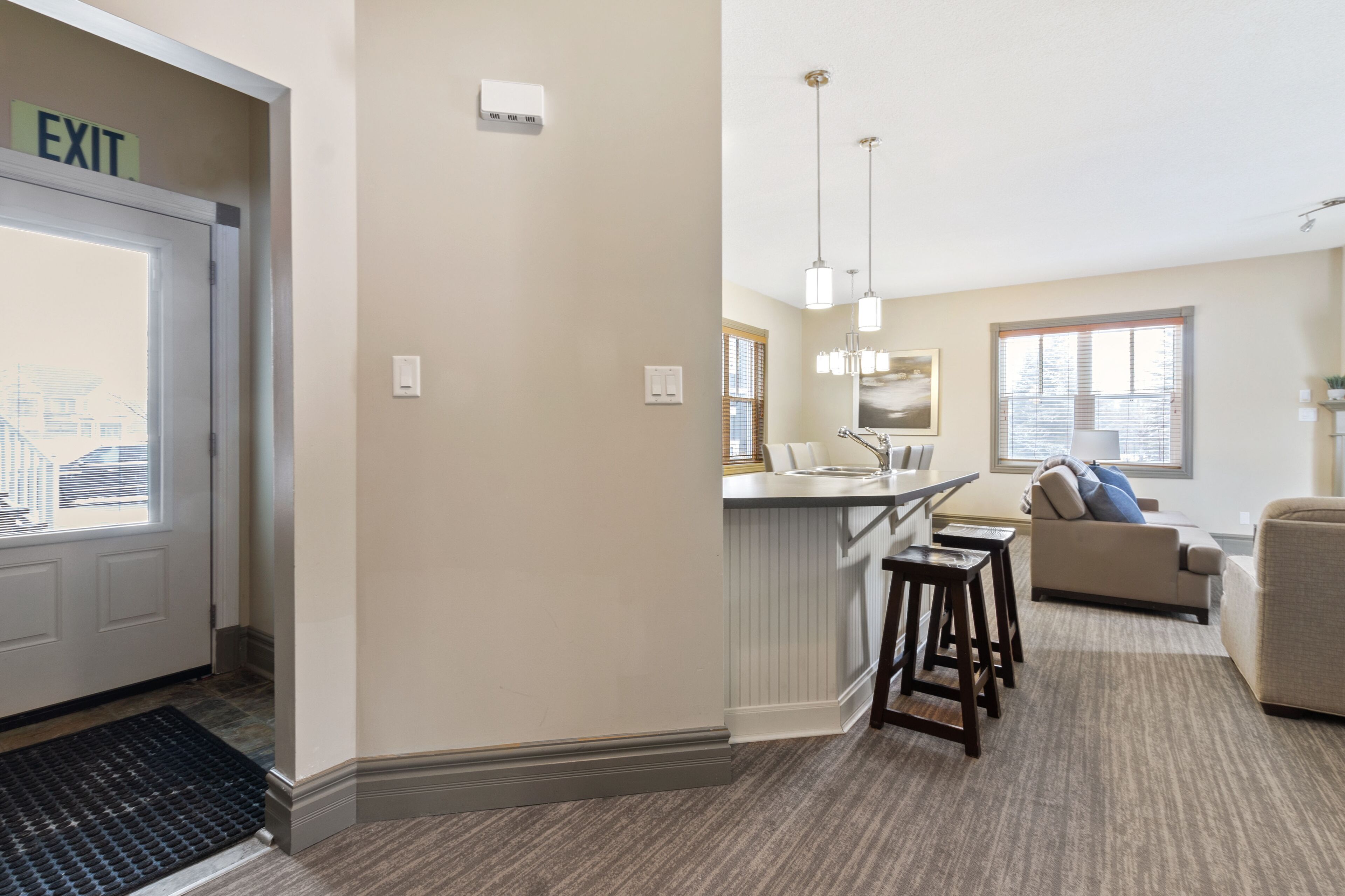 Un appartement moderne comprenant un coin cuisine, un salon avec un canapé et un coin repas avec des tabourets.