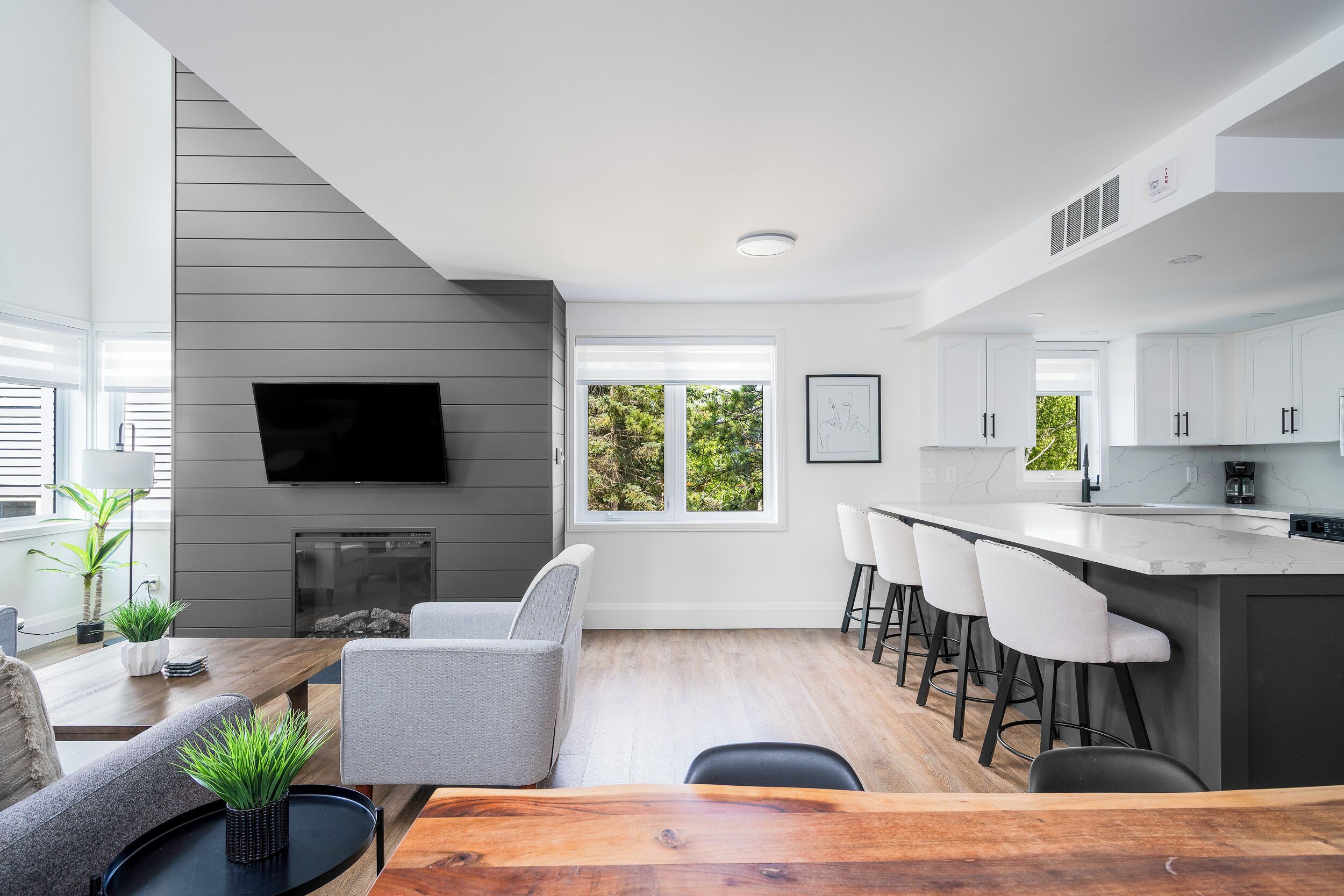 A modern kitchen with a large island, bar stools, and a flat-screen TV mounted on the wall.