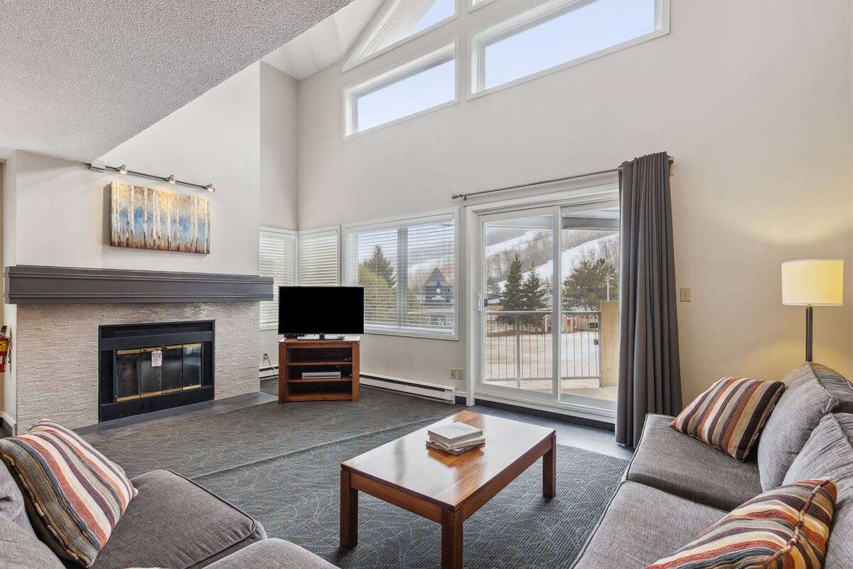 A modern living room with a fireplace, a flat-screen TV, and a sofa with striped pillows.