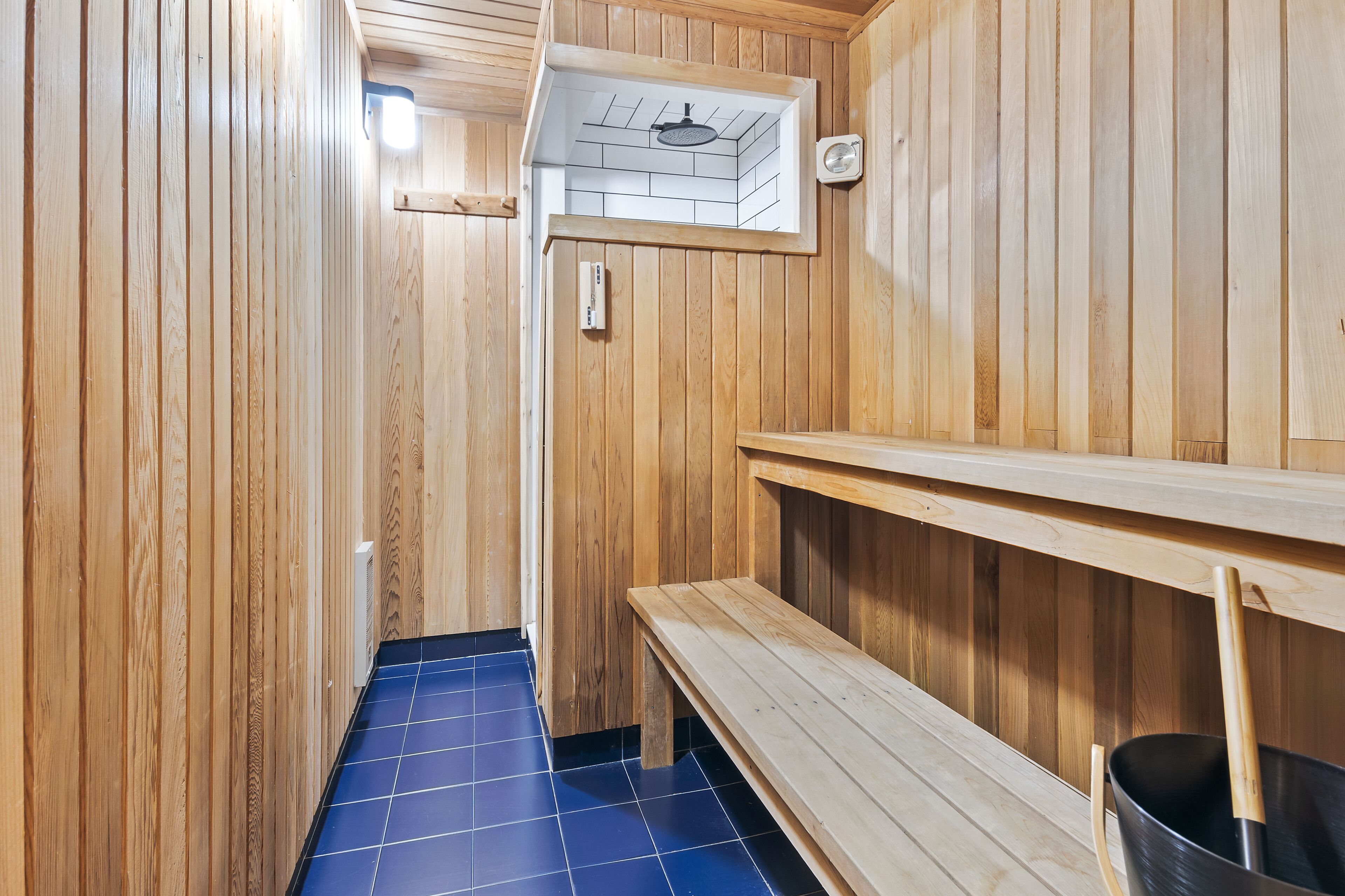 Una sauna con paredes de madera y suelo cubierto de azulejos azules.