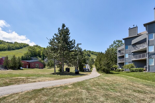 A residential area with a paved path, a red building, and a multi-story gray building with balconies.