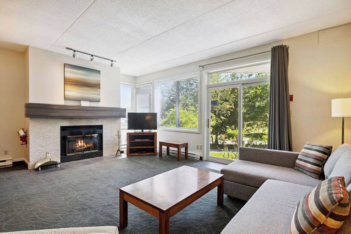 A living room with a fireplace, a sofa, a coffee table, and a television.