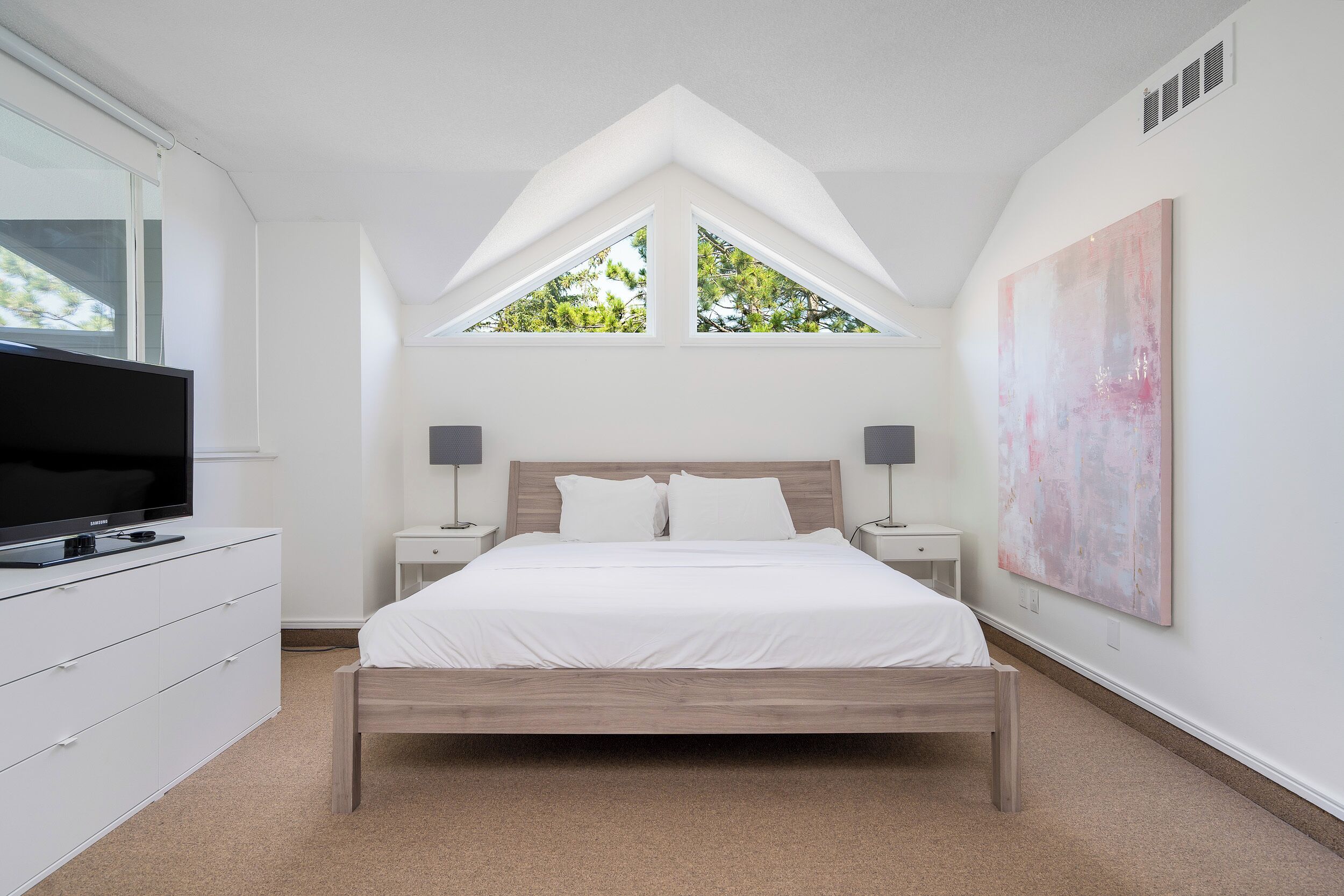 Ein Schlafzimmer mit Bett, Fernseher, Kommode und einem Bild an der Wand.