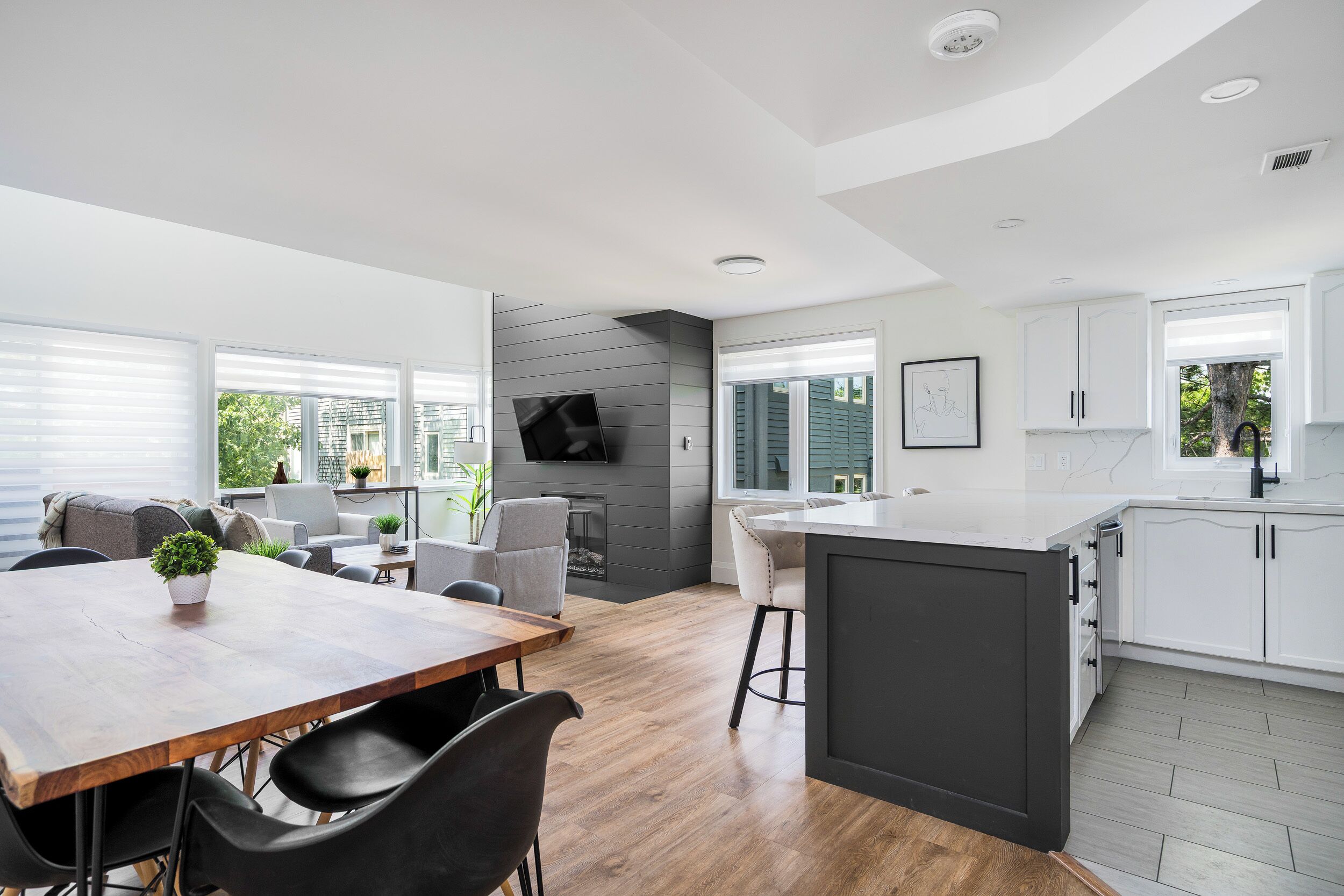 A modern kitchen with white cabinets, a wooden dining table, and a built-in island.