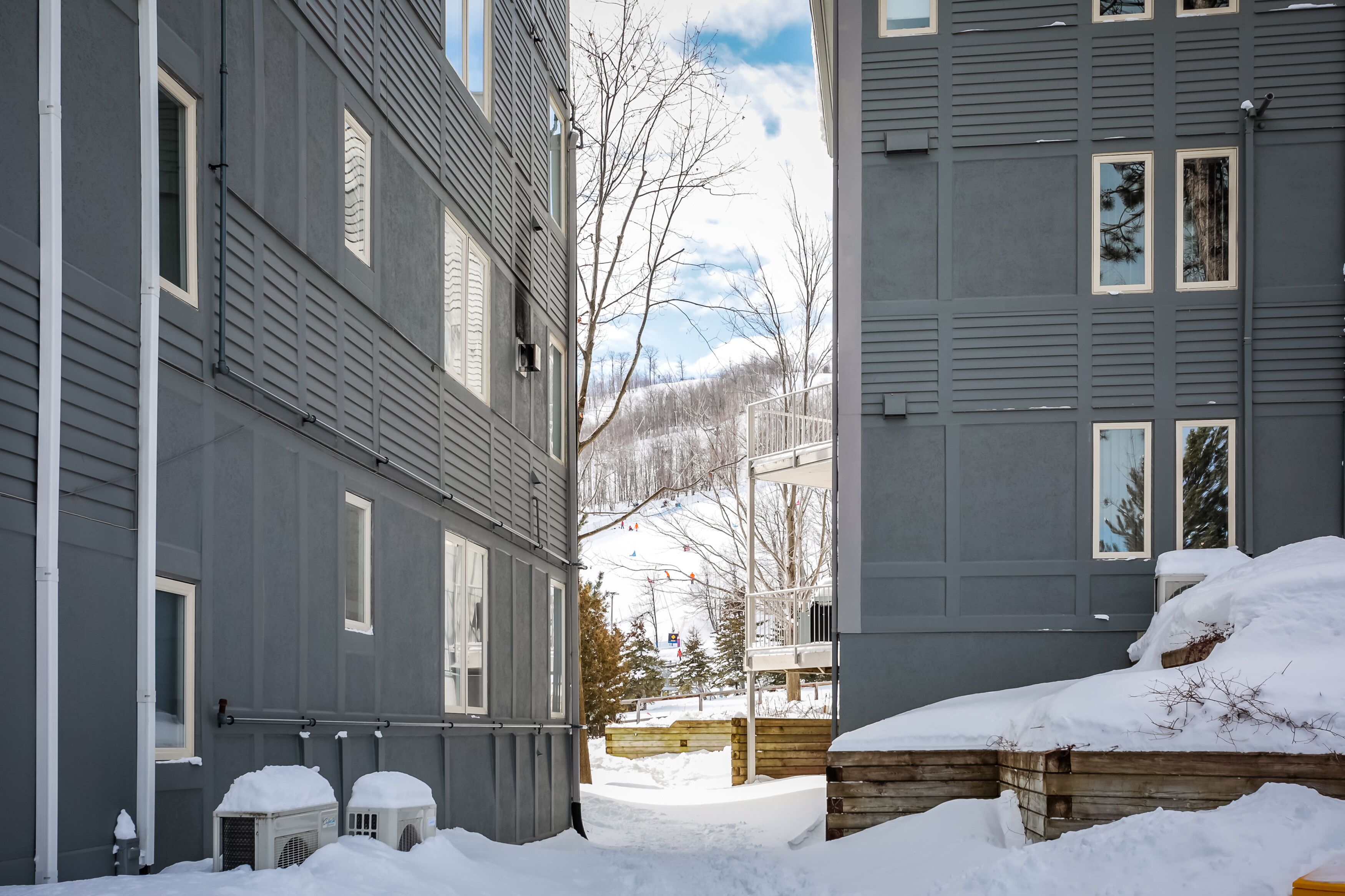 A residential building with multiple windows and a snow-covered ground.