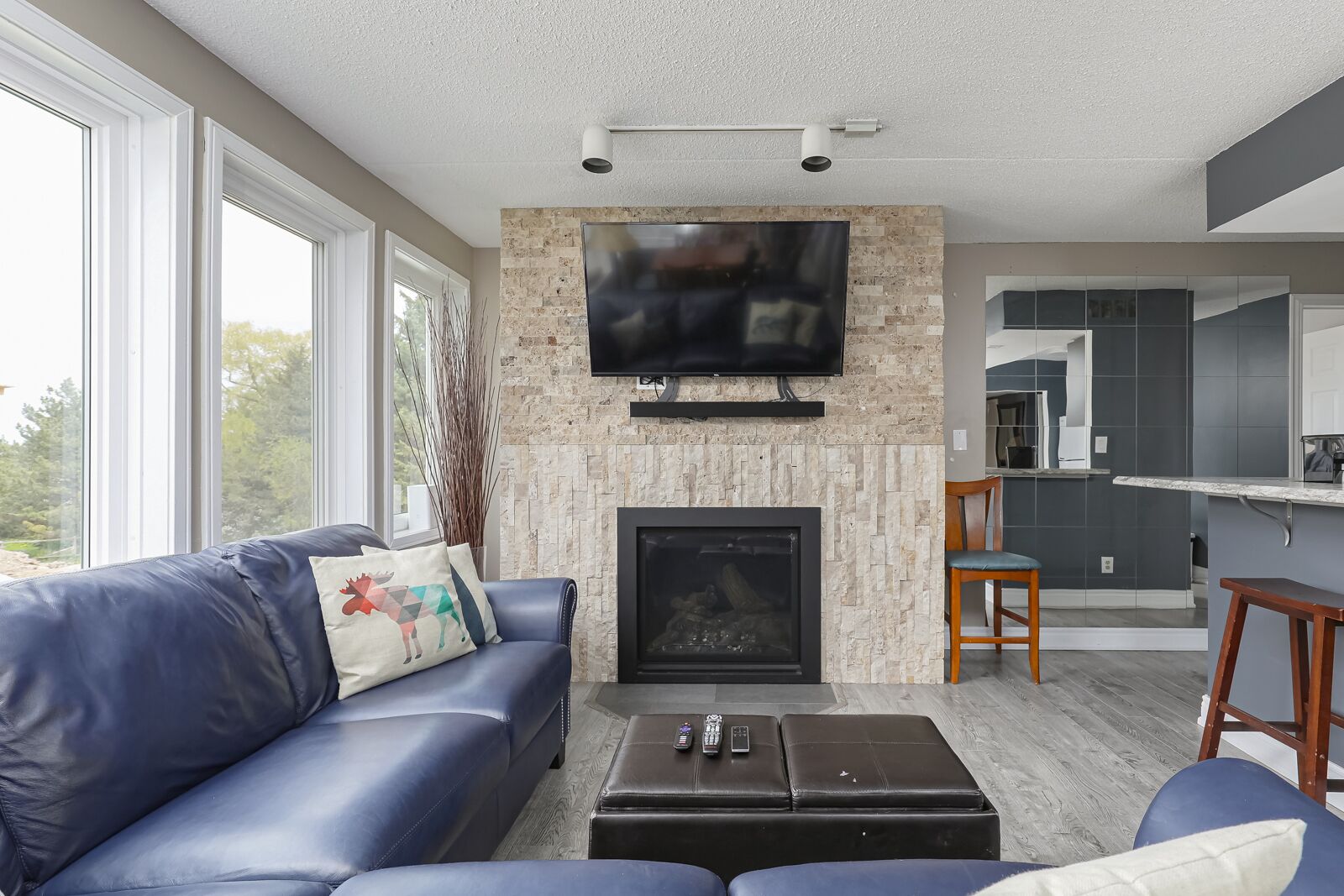 Una sala de estar con chimenea, televisor montado encima, un sofá con cojines decorativos y una mesa de centro.