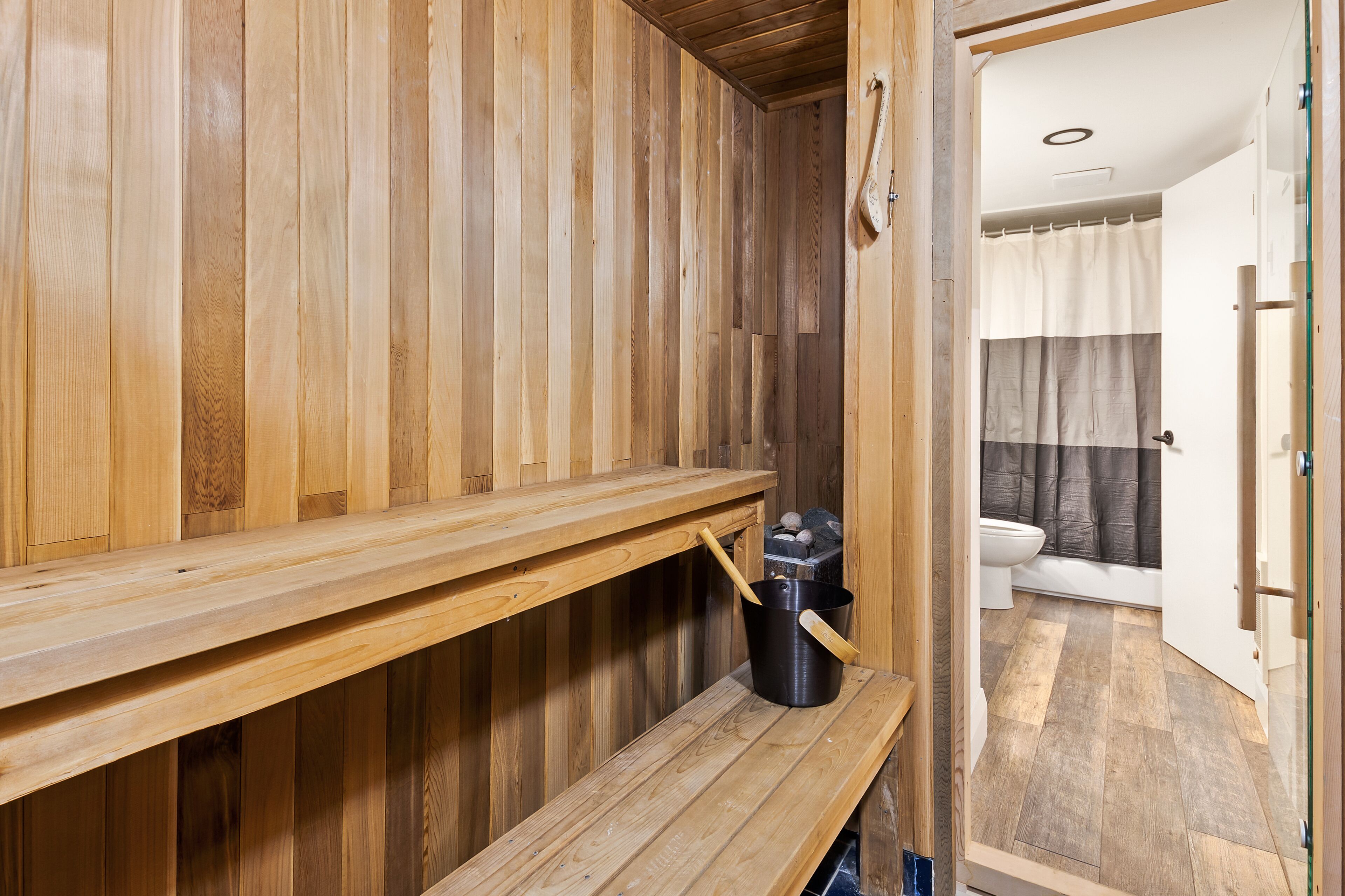 A wooden sauna with benches and a bucket.