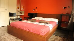 Een slaapkamer met een houten bed, een stoel, een bureau en een nachtkastje met lampen.