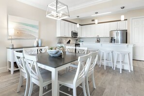 A modern kitchen with white cabinetry, a central island, and pendant lighting. - Beautiful Condo with Pool Cabana at Sanctuary at Redfish (Santa Rosa Beach)