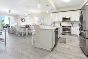 A modern kitchen with white cabinetry, stainless steel appliances, and a central island. - Beautiful Condo with Pool Cabana at Sanctuary at Redfish (Santa Rosa Beach)