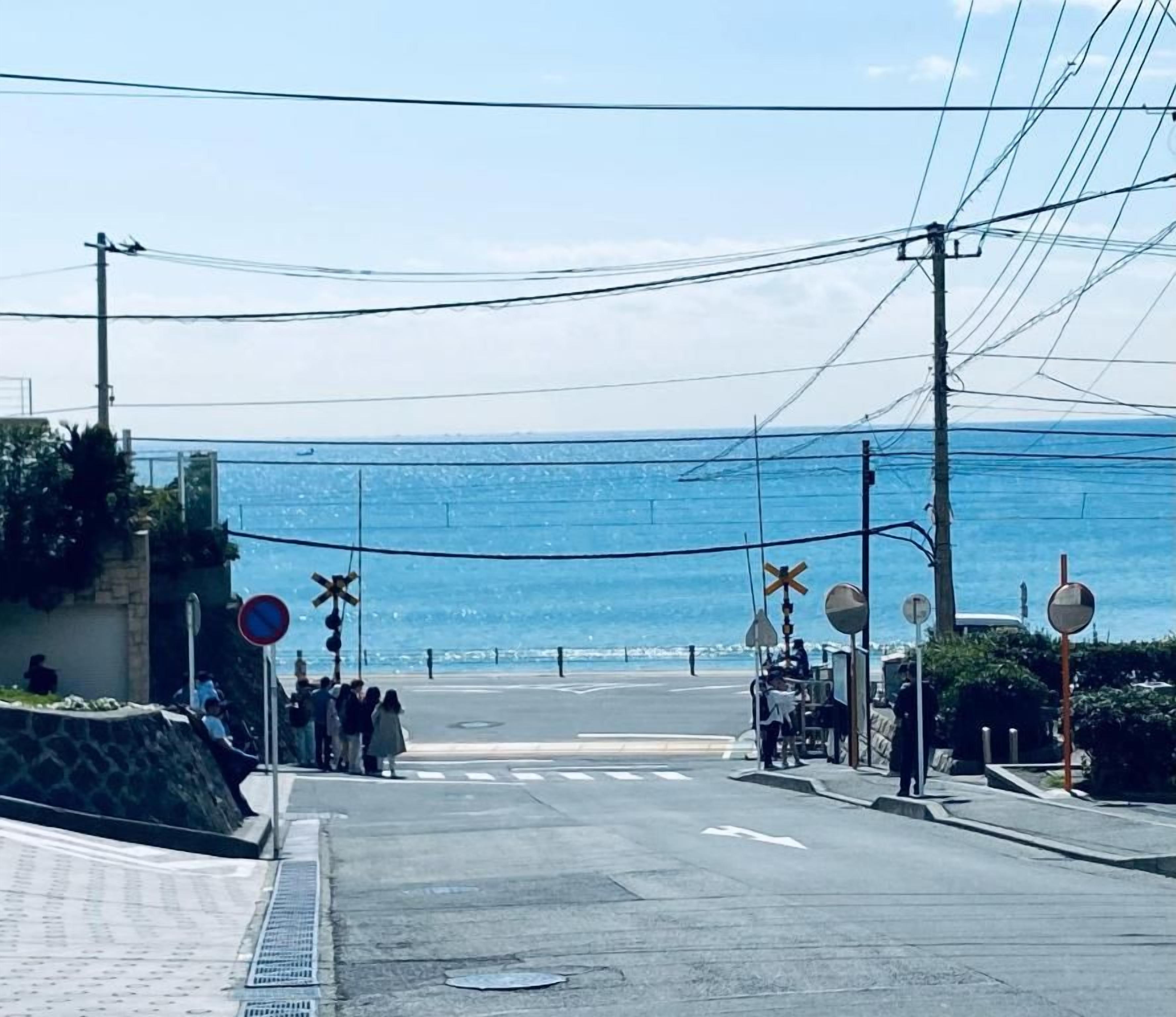 Una carretera costera con un paso de peatones, un cruce ferroviario y vistas al mar.